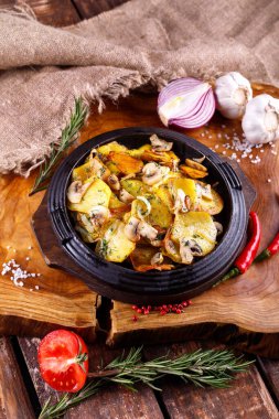 Ahşap bir tahtanın arka planında, et kaplı kızarmış patates.