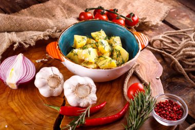 Tahta bir arka planda sebzelerin yanında dereotlu ve tereyağlı haşlanmış patates.