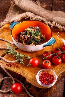 Tahta arka planda sebzelerin yanında peynirli ızgara karnabahar.