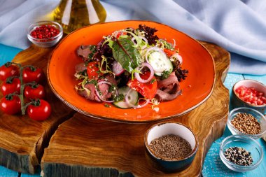 Dilimlenmiş biftekli salata, domates, ahşap arka planda bir tabakta salatalık.