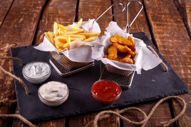 Patates kızartması ve patates kızartması masanın arkasındaki sosun yanında.