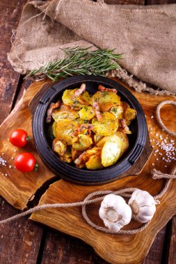 Ahşap bir tahtanın arka planında, et kaplı kızarmış patates.