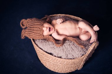 Örgü şapkalı, battaniyenin üstünde uyuyan yeni doğmuş bir çocuk sepette yatıyor. en üstteki görünüm.