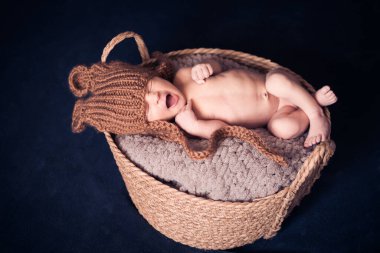 Örgü şapkalı, battaniyenin üstünde uyuyan yeni doğmuş bir çocuk sepette yatıyor. en üstteki görünüm.