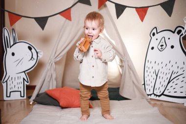 Çadırda oynayan şirin bir çocuk. Pantolon ve bej bir gömlek giymiş.