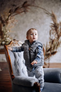 Bir yaşında bir çocuk yatak odasındaki sandalyede oturuyor.