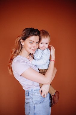 Genç ve mutlu bir anne, bir yaşındaki oğlunu kollarına alır.