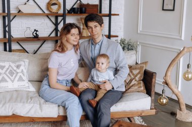 Ebeveynler kucağında küçük bir oğul taşırlar. Mutlu aile kavramı.