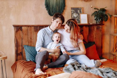 Ebeveynler kucağında küçük bir oğul taşırlar. Mutlu bir aile, annelik ve ebeveynlik kavramı..