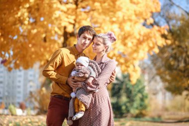 Aile-baba, anne-oğul sonbahar parkında eğleniyorlar.