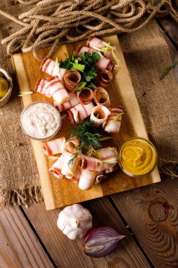 Tahta üzerinde domuz pastırması, sonraki sos, soğan, ahşap masa arkaplanı.