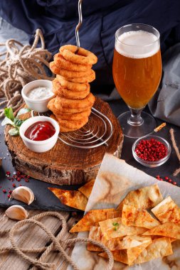 Ahşap bir masa üzerinde bira soslu kızarmış soğan halkaları.