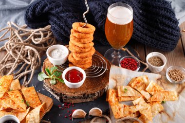 Ahşap bir masa üzerinde bira soslu kızarmış soğan halkaları.