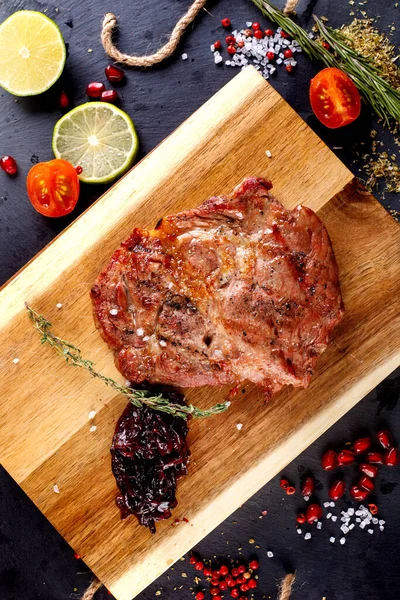 Schweinesteak Mit Paprika Und Soße Auf Einem Schneidebrett Gegen Einen — Stockfoto