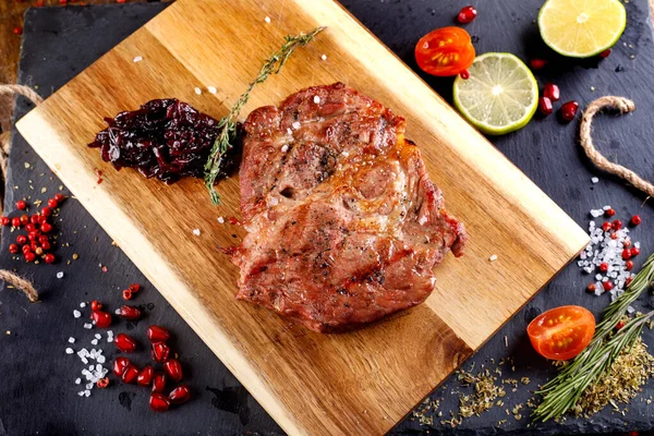 Vepřový Steak Pálivou Paprikou Omáčkou Řezacím Prkně Proti Dřevěnému Stolu — Stock fotografie