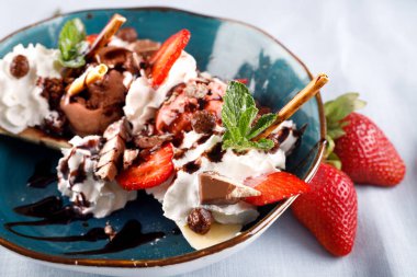 Masa örtüsünün üzerinde taze böğürtlenli dondurmalı tatlı.