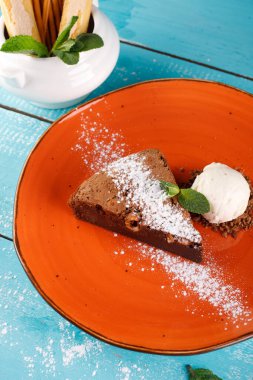 Badem ve nane dilimleri serpiştirilmiş brovniler, turuncu bir tabağa dizilmiş..