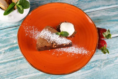 Badem ve nane dilimleri serpiştirilmiş brovniler, turuncu bir tabağa dizilmiş..