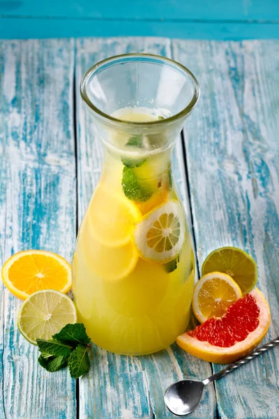 A glass of lemon soda with fresh mint on a blue wooden background