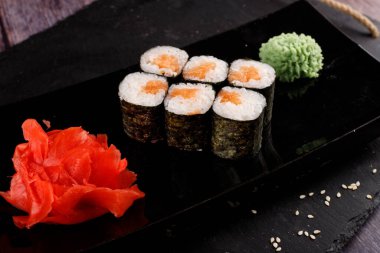 Siyah arka planda wasabi ve zencefilli fırında suşi ruloları. Japon Doğu mutfağı.
