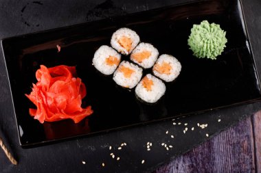 Siyah arka planda wasabi ve zencefilli fırında suşi ruloları. Japon Doğu mutfağı.