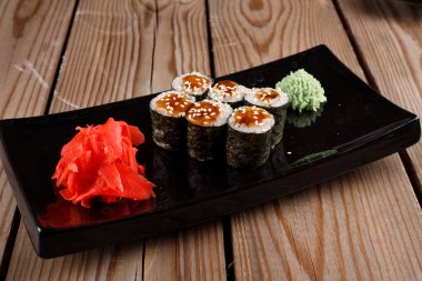 Siyah arka planda wasabi ve zencefilli fırında suşi ruloları. Japon Doğu mutfağı.