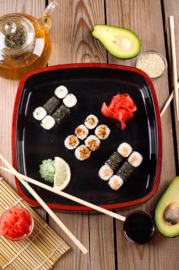 Siyah arka planda wasabi ve zencefilli fırında suşi ruloları. Japon Doğu mutfağı.