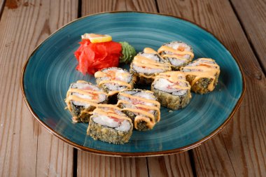 Pişmiş suşi, üzerine susam tohumları serpiştirilmiş ekmekler, mavi bir tabakta yakın plan.