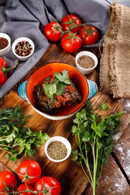 Üzüm yapraklarıyla doldurulmuş pirinç ve et. Yukarıdan manzara. Koyu tahta arkaplan.