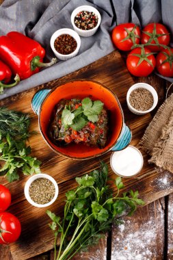 Üzüm yapraklarıyla doldurulmuş pirinç ve et. Yukarıdan manzara. Koyu tahta arkaplan.