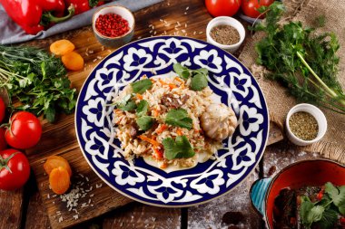 Doğu mutfağı kavramı. Ev yapımı Özbek pilavı veya kuzu pilavı, ahşap bir masanın arka planında bir tabakta servis edilir.