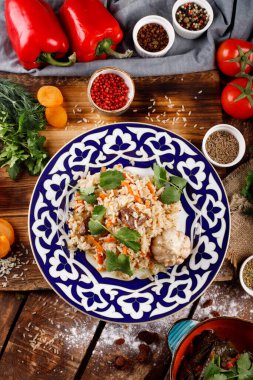 Doğu mutfağı kavramı. Ev yapımı Özbek pilavı veya kuzu pilavı, ahşap bir masanın arka planında bir tabakta servis edilir.