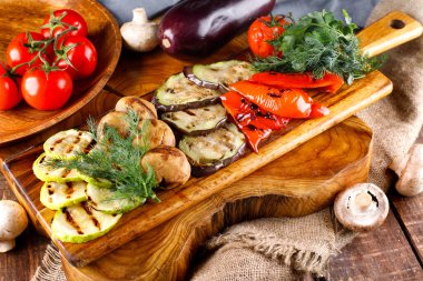 Tahta bir arka planda kesme tahtasında kızarmış sağlıklı sebzeler.