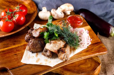 Sulu kızarmış tavuk bacağı ve yanında soslu et ve kesim tahtasındaki malzemeler.