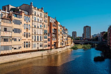 Renkli sarı ve turuncu evler ve Pont de Sant Agusti köprüsü Girona, Katalonya, İspanya 'daki Onyar su nehrine yansıdı. Arka planda Sant Feliu Kilisesi ve Saint Mary Katedrali.
