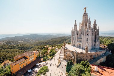 Tibidabo church on mountain in Barcelona with christ statue overviewing the city clipart