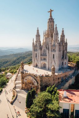 Tibidabo church on mountain in Barcelona with christ statue overviewing the city clipart