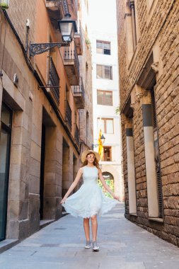 Mavi elbiseli genç bir kız bir yaz günü Barselona şehrinde yürür.