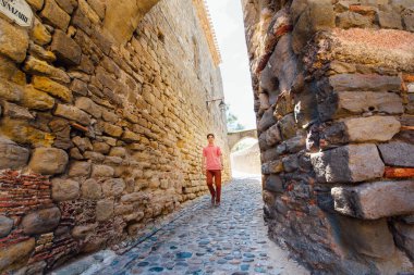 Genç bir adam, güneşli bir günde Fransa 'nın ortaçağ şehri Carcassonne' da bir sokakta duvara karşı koşar.