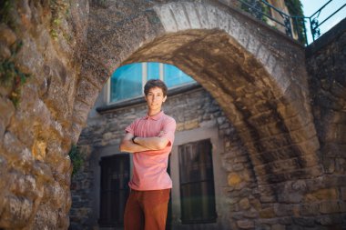 Genç bir adam, güneşli bir günde Fransa 'nın ortaçağ şehri Carcassonne' da bir sokakta bir duvara karşı duruyor.