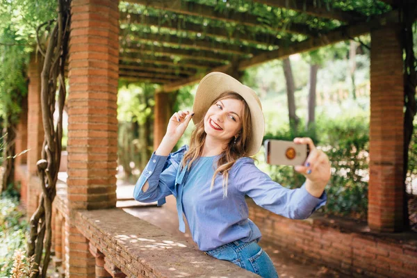 夏天的一天 一个时髦的女孩在巴塞罗那街上拿着智能手机 一边笑一边自私自利 — 图库照片