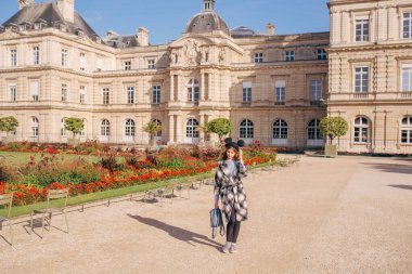 Lüksemburg bahçesindeki mikimaus şapkalı ve Paris 'teki saraydaki mutlu kız. Evden uzakta ev kavramı.