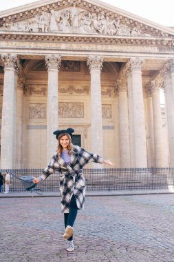 Mikimaus şapkası takan ve sırt çantası taşıyan genç bir kadın Pantheon, Paris, Fransa meydanında yürüyor.