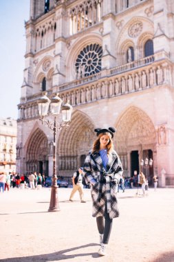 Notre Dame 'ın Paris Katedrali' nin arka planında güzel bir paltoyla mikimaus şapkalı güzel bir kız.