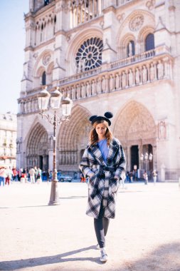Notre Dame 'ın Paris Katedrali' nin arka planında güzel bir paltoyla mikimaus şapkalı güzel bir kız.