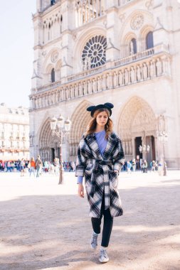 Notre Dame 'ın Paris Katedrali' nin arka planında güzel bir paltoyla mikimaus şapkalı güzel bir kız.