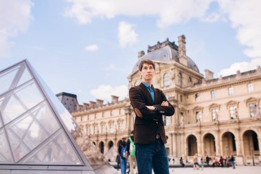 Louvre binasının arka planında genç bir adam duruyor. Paris, Fransa