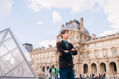 Louvre binasının arka planında genç bir adam duruyor. Paris, Fransa