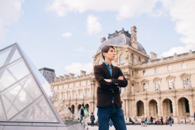 Louvre binasının arka planında genç bir adam duruyor. Paris, Fransa