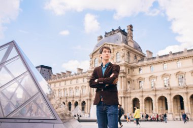 Louvre binasının arka planında genç bir adam duruyor. Paris, Fransa